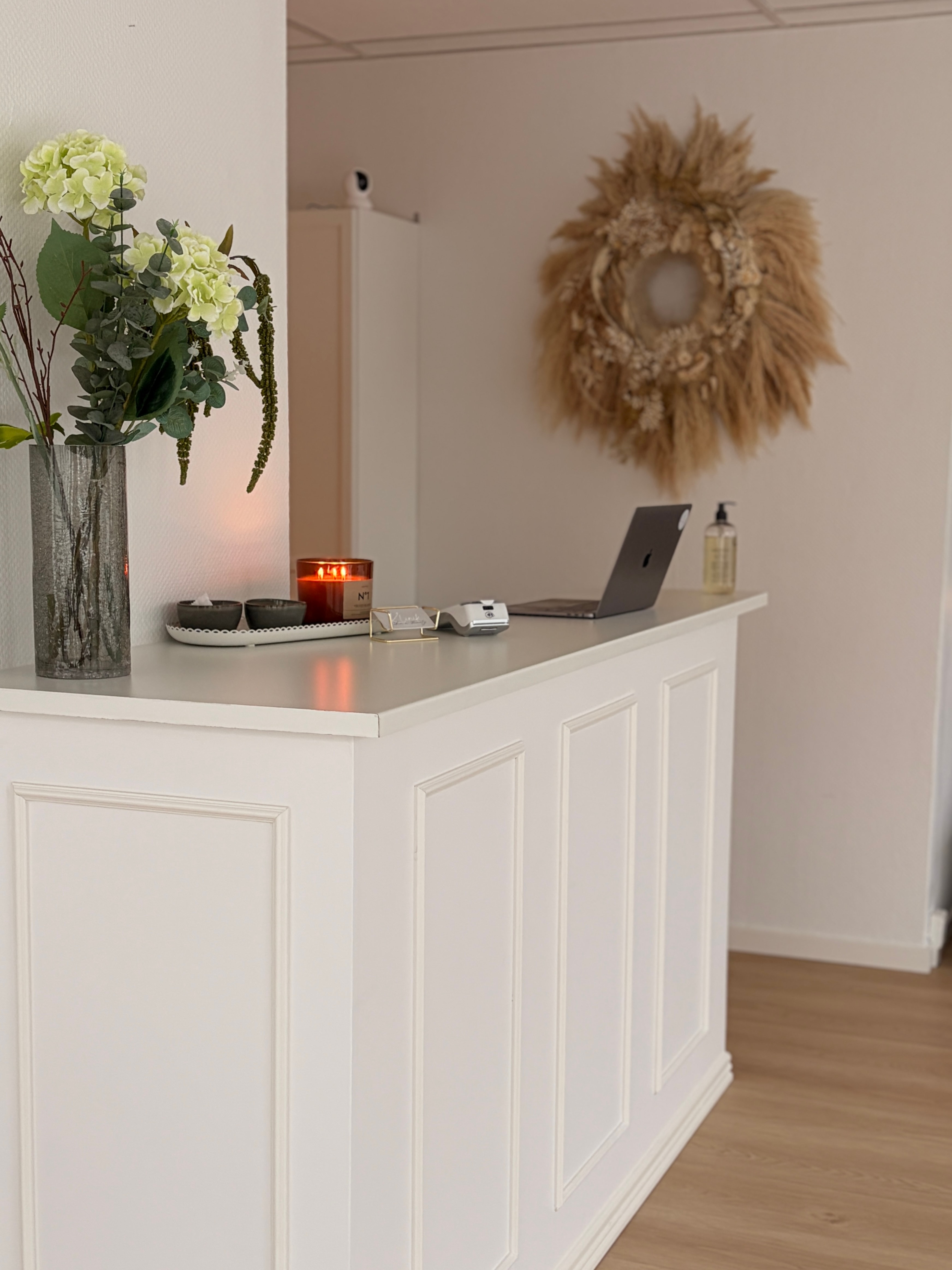 Klinikkens reception på Vestergade med blomster, levende lys og varme naturmaterialer